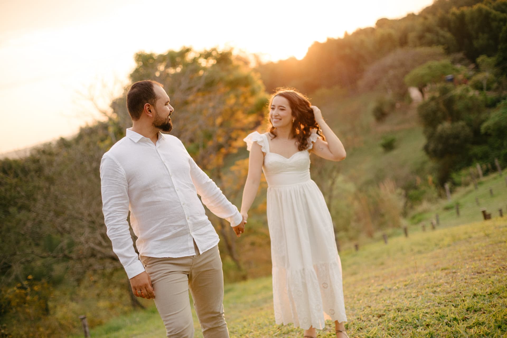 Daniela e Wennder de mãos dadas no campo ao entardecer